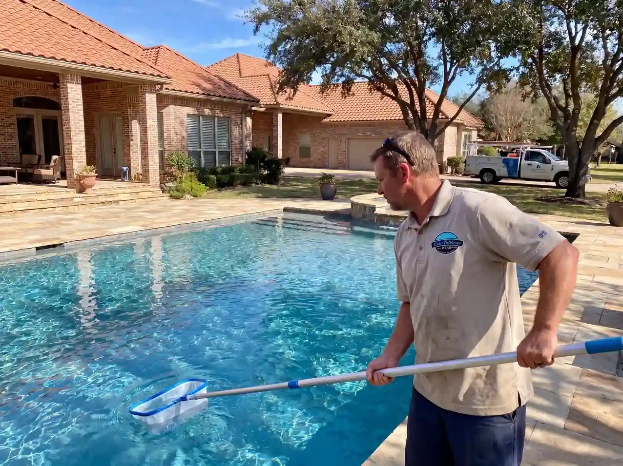 Pool technician skimming surface debris during weekly service